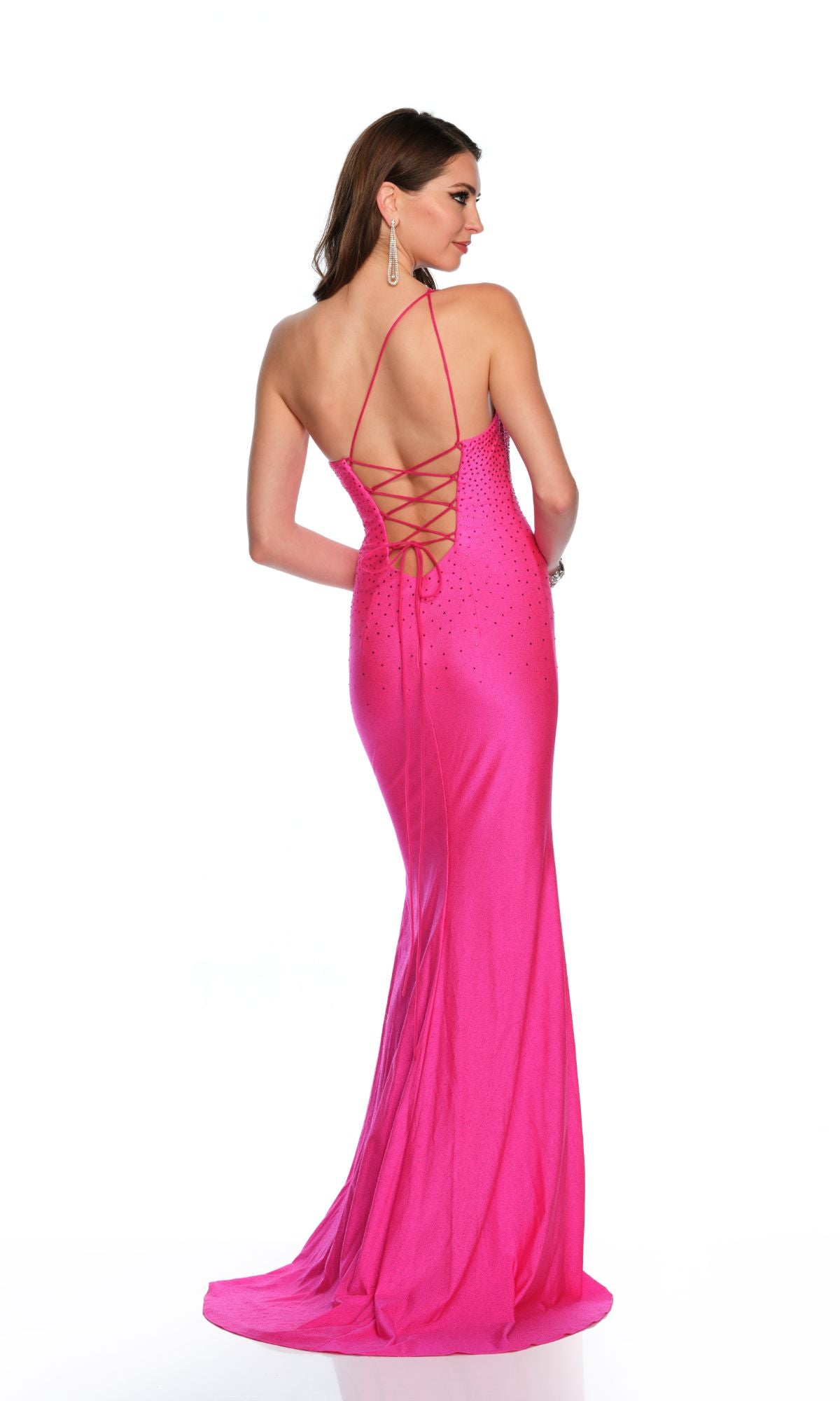 A woman stands against a white background wearing the Dave and Johnny Long Formal Dress 11528, a floor-length, backless fuchsia pink gown featuring lace-up detailing, as she looks to the side.